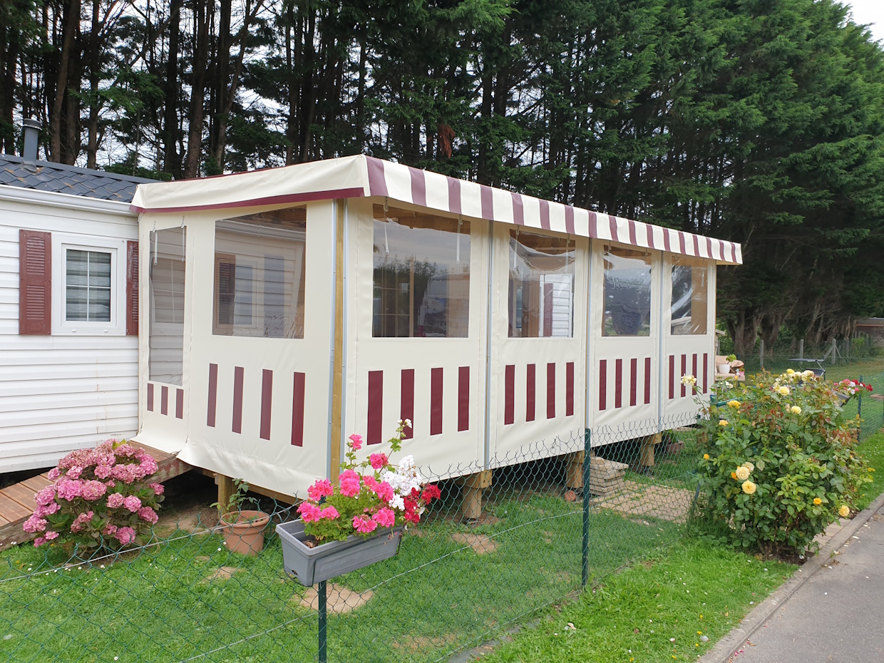 Mobil-home avec auvent et fleurs colorées devant.