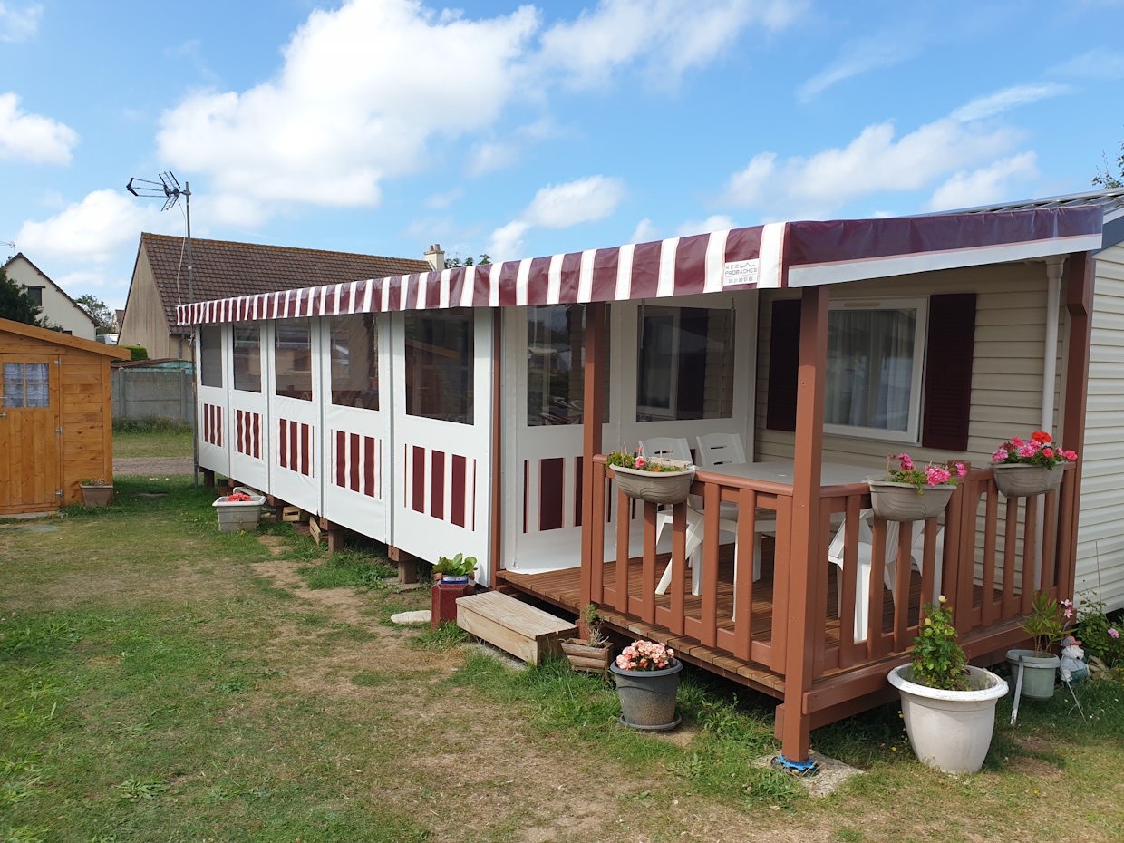 Mobil-home avec terrasse et jardinières fleuries.