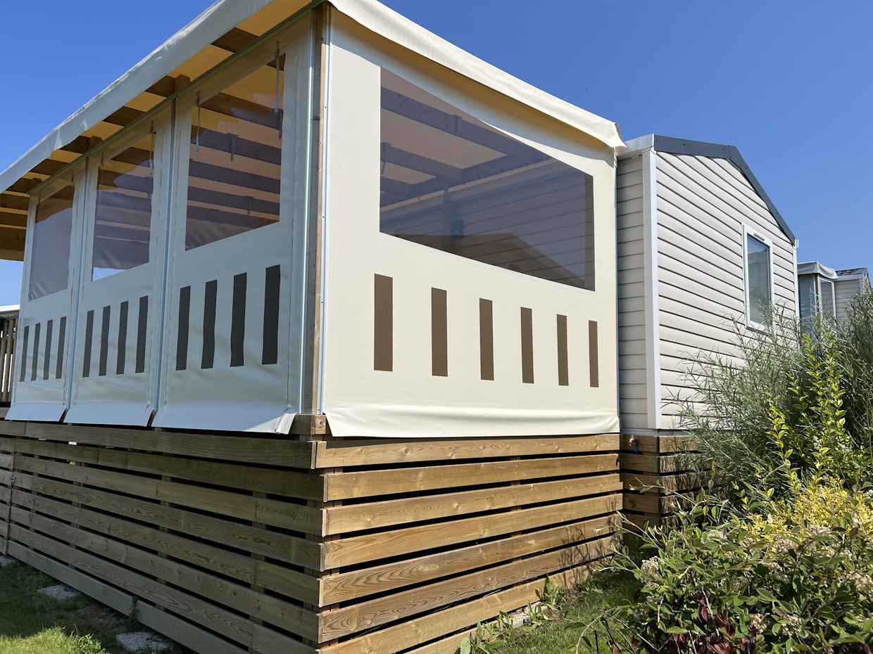 Mobil-home avec terrasse couverte en bois.