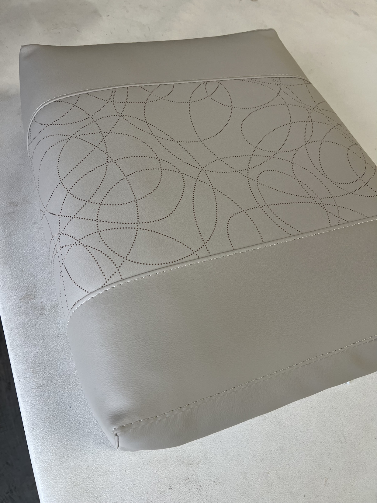 Coussin en cuir beige avec motifs, vu de près.